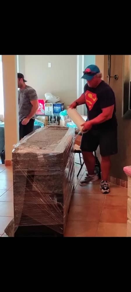 Mover securing a heavy wrapped item with straps for a careful lift